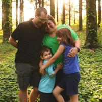 The Middleton family stops for a group hug and photo in a lush forest.