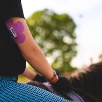 Kara rides her horse. Her insulin pump is visible on the back of her upper arm.