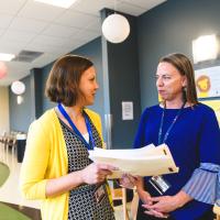 Diabetes educators Angela and Deb review some files in a hallway.