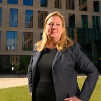 A photo of Dr. Kolesar posing confidently with her hands on her hips in front of a building on the UK HealthCare medical campus.