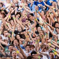 A shot of the crowd at a DanceBlue event, they are seen smiling and holding their arms up in the air.