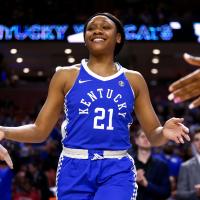 Ogechi walks out onto the court, smiling and looking strong and confident. She is receiving high fives from people on either side of her.