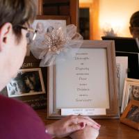 Debbie pauses for a moment in front of a bunch of framed photographs. She's looking at a framed print that says \