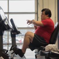 Roger checks his heartbeat while biking on a stationary bike machine.