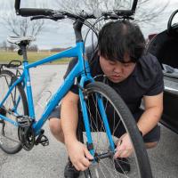 Roger hunkers down to work on tightening the front wheel of his bike before a ride.