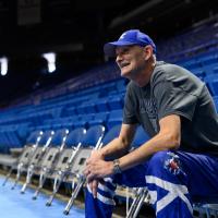 A candid photo of Andy sitting in a courtside chair and looking off camera with a smile on his face.