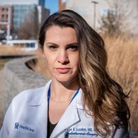 A close-up photo of Dr. Tessa London-Bounds standing by the bushes outside one of the medical buildings on the UK HealthCare campus.