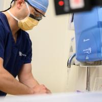 Dr. Warriner stands over a sink washing his hands, while prepping for surgery.