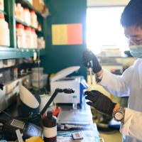 A photo of Ronnie in a laboratory setting, as he carefully extracts a sample from a vial.