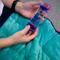 A close-up photo of Dr. Rhodus holding an hourglass-shaped device containing water and colored oil.