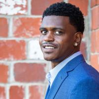 A portrait of Terry, dressed in a blue blazer and a button-down, looking over his left shoulder and smiling at the camera.