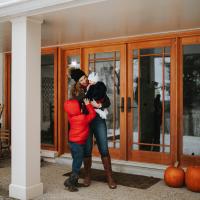 Dr. London-Bounds is standing outside her home, laughing and cuddling her daughter, while her son stands in front of her and reaches up to his sister.