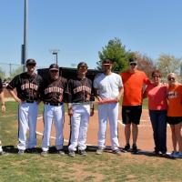 Trent poses for a photo on a baseball field, surrounded by his teammates and his family members, holding a baseball bat.