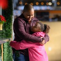 A photo of Essence looking up at Whitley as they hug.