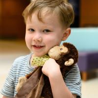 Ezra cuddles his Stinky Monkey close and smiles.