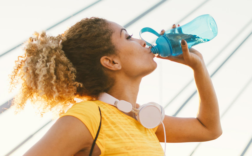 A woman drinks from a water bottle.