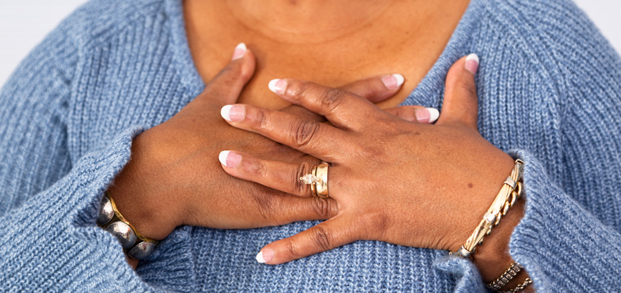 A woman with hands placed on her heart.