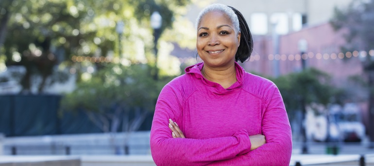 Woman wearing pink crosses her arms.