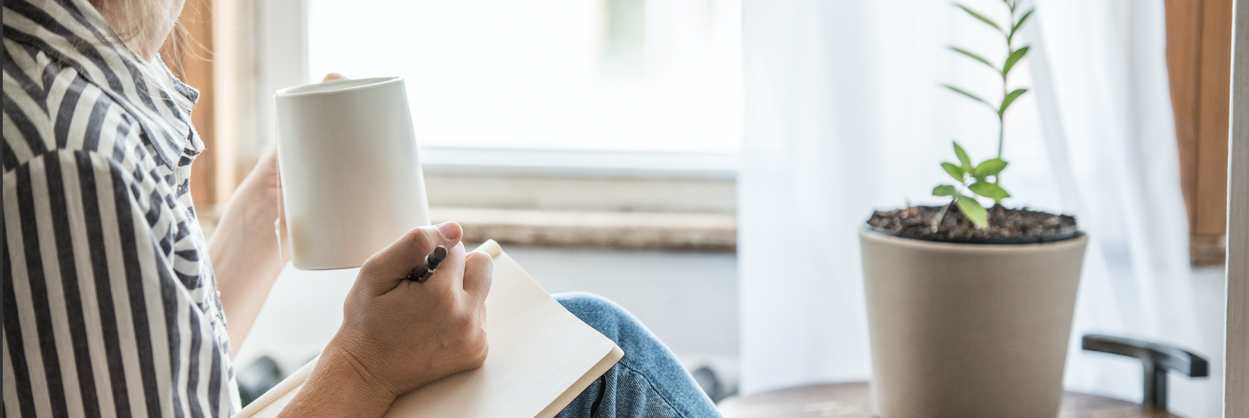 A woman writing in journal and relaxing with tea.