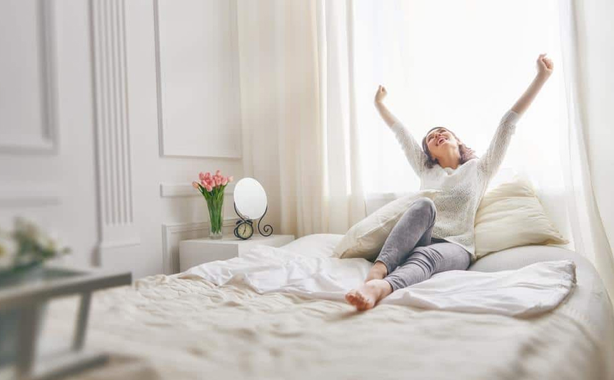 A woman waking up stretches.