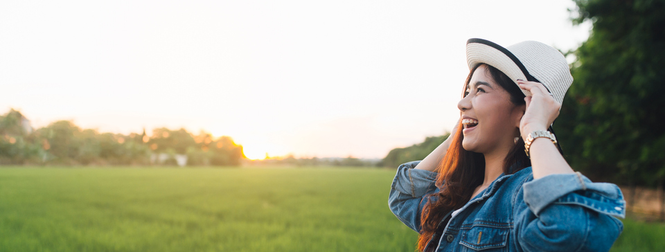 A young woman stands in a grassy field and smiles.